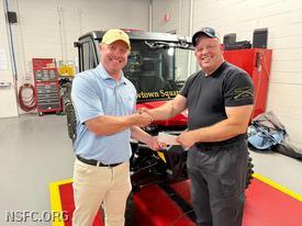 Tyler Curtis, Championship Operations Manager for the PGA of America delivers the title for our new CanAm ATV to Fire Chief Chris Young.